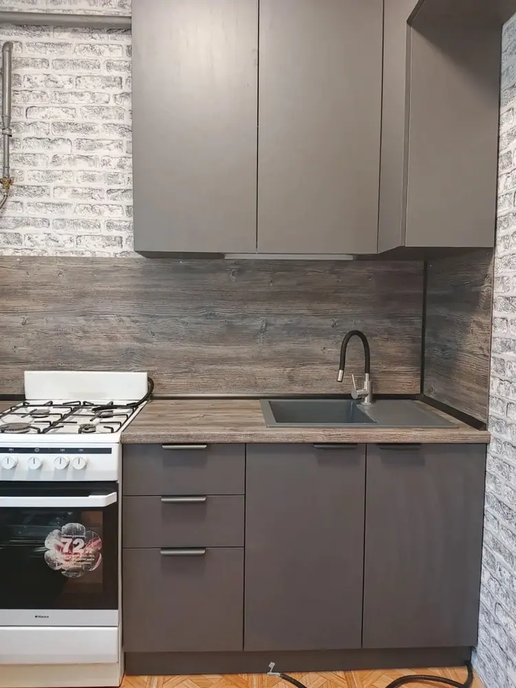 Серая кухня с фартуком под дерево и белой кирпичной стеной